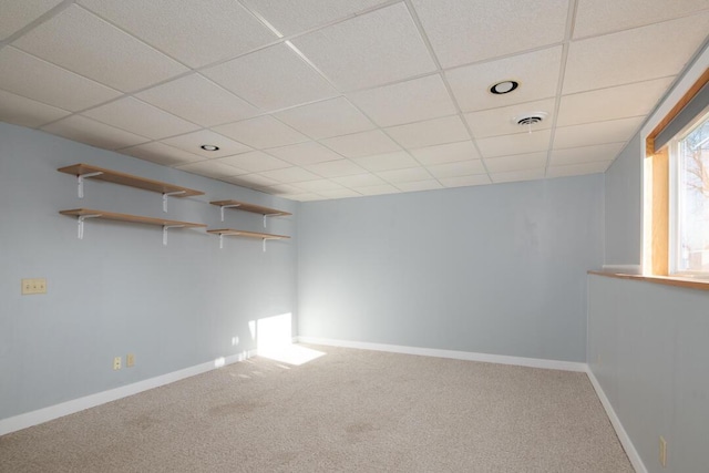 basement featuring a drop ceiling, visible vents, baseboards, and carpet flooring