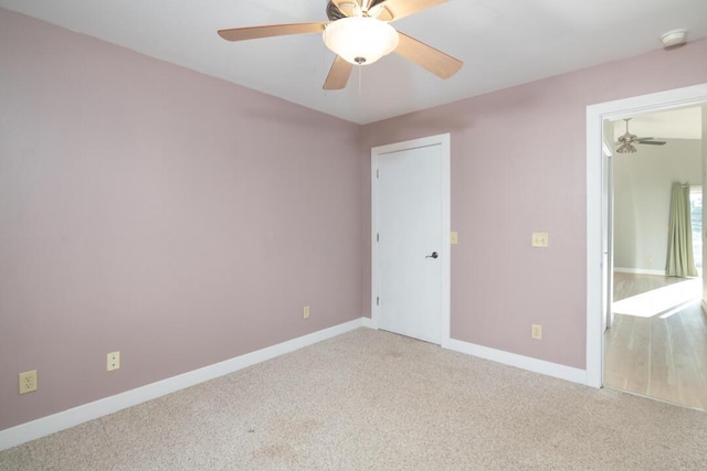 carpeted spare room with ceiling fan and baseboards