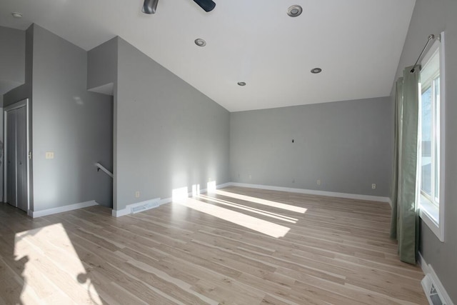 empty room featuring vaulted ceiling, visible vents, and light wood-type flooring