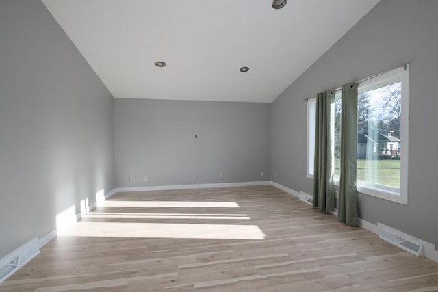 spare room with visible vents, light wood-style flooring, and vaulted ceiling