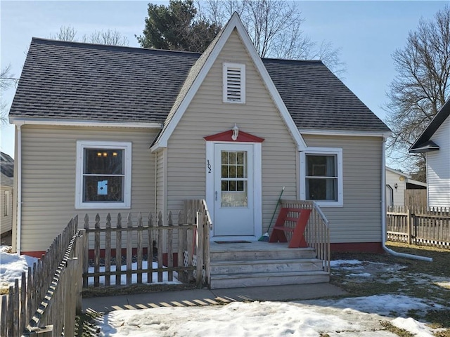 view of front of home with a shingled roof and fence