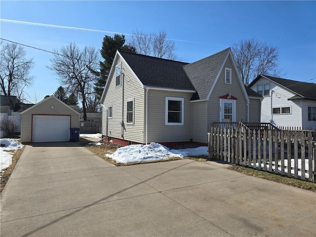 view of front of house featuring a detached garage, fence, an outdoor structure, concrete driveway, and a shingled roof