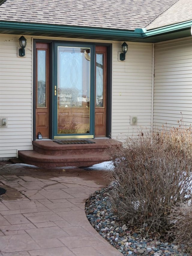 doorway to property with roof with shingles