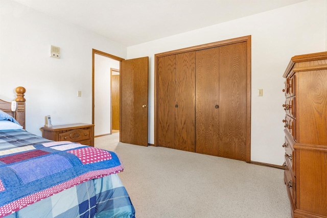 bedroom featuring a closet, baseboards, and light colored carpet