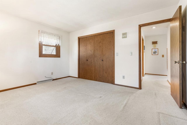 unfurnished bedroom with a closet, baseboards, light colored carpet, and a baseboard radiator