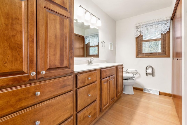 bathroom with vanity, toilet, visible vents, and plenty of natural light