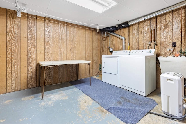 laundry room with laundry area, wooden walls, washing machine and dryer, and a sink