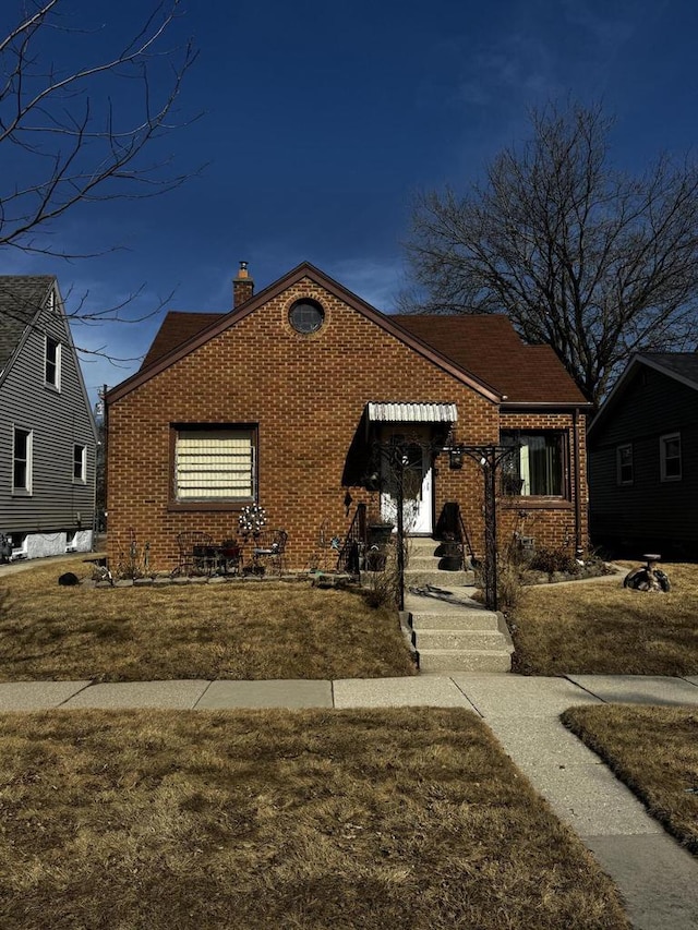 bungalow-style home featuring brick siding and a chimney