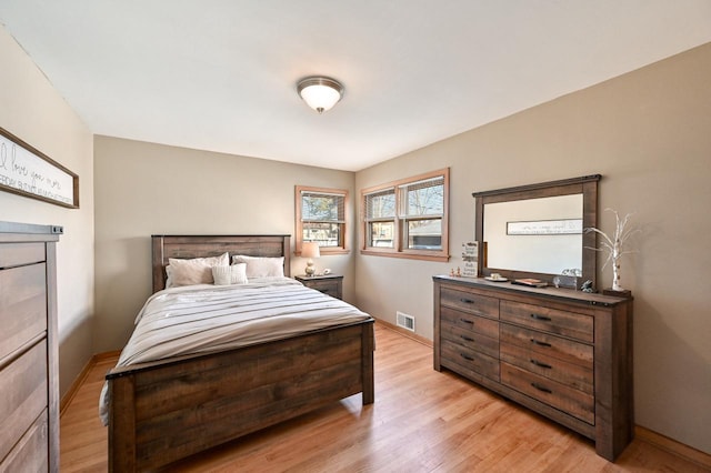 bedroom with baseboards, visible vents, and light wood finished floors