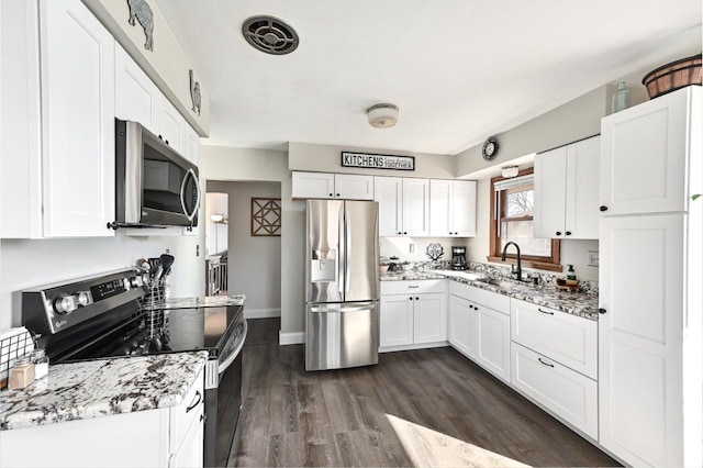 kitchen with a sink, stainless steel appliances, dark wood-style flooring, and white cabinetry