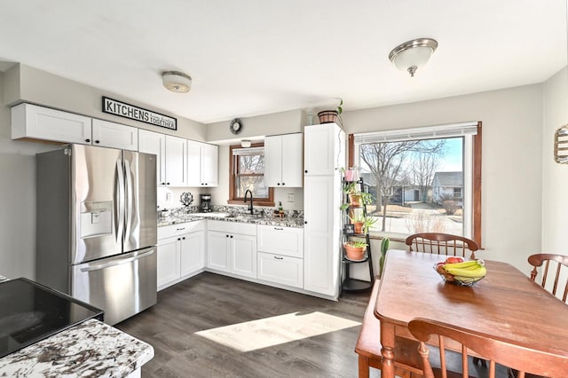 kitchen featuring dark wood finished floors, stainless steel fridge, white cabinets, and a sink