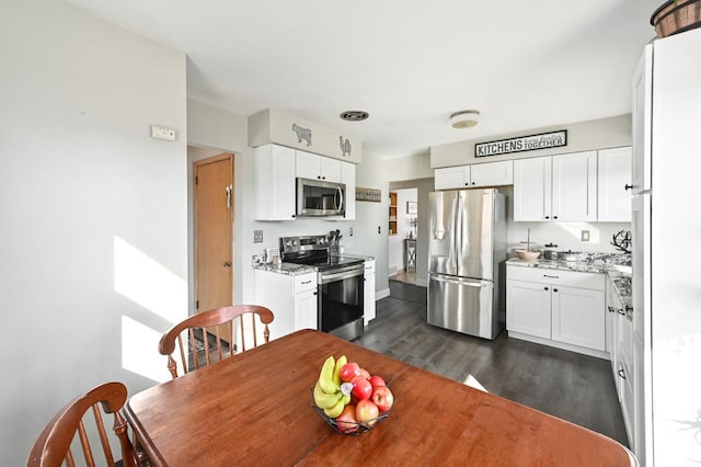 kitchen with appliances with stainless steel finishes, dark wood-style floors, and white cabinetry