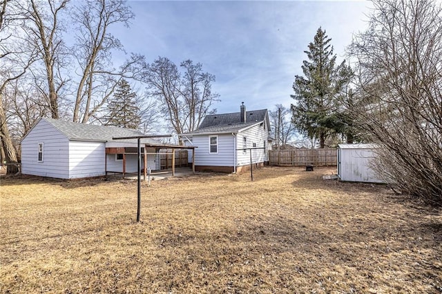 back of property with fence, a shed, a lawn, a chimney, and an outdoor structure