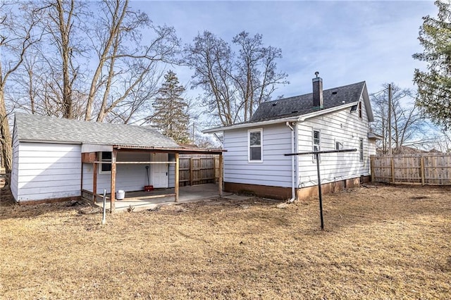 back of house featuring a patio, a shingled roof, a chimney, and fence