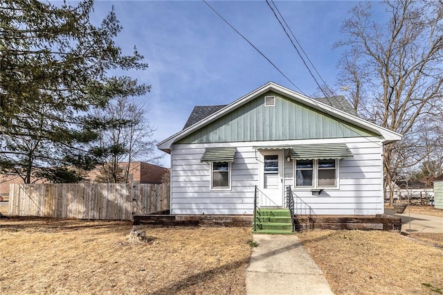 bungalow featuring a shingled roof and fence