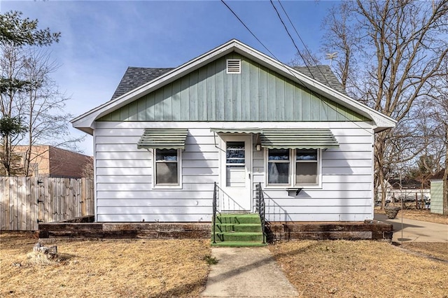 bungalow-style home with fence and roof with shingles