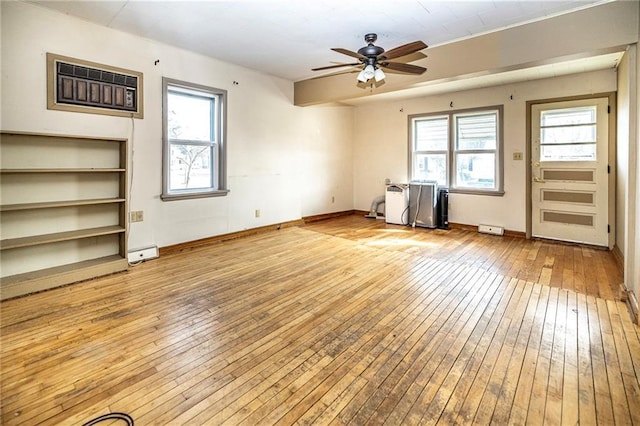 unfurnished living room with a wealth of natural light, light wood-style flooring, baseboards, and ceiling fan