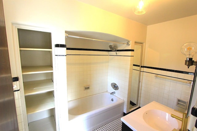 bathroom with wainscoting, tile walls, vanity, and  shower combination