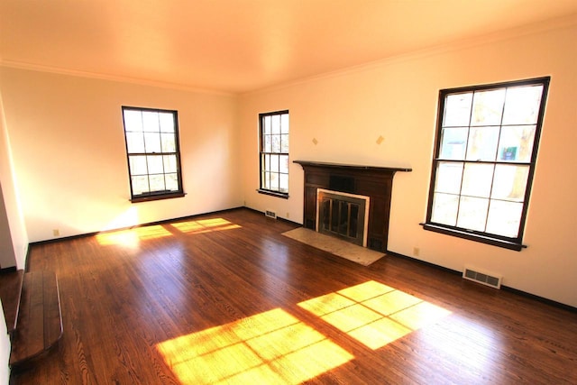 unfurnished living room with visible vents, crown molding, a fireplace with flush hearth, and wood finished floors