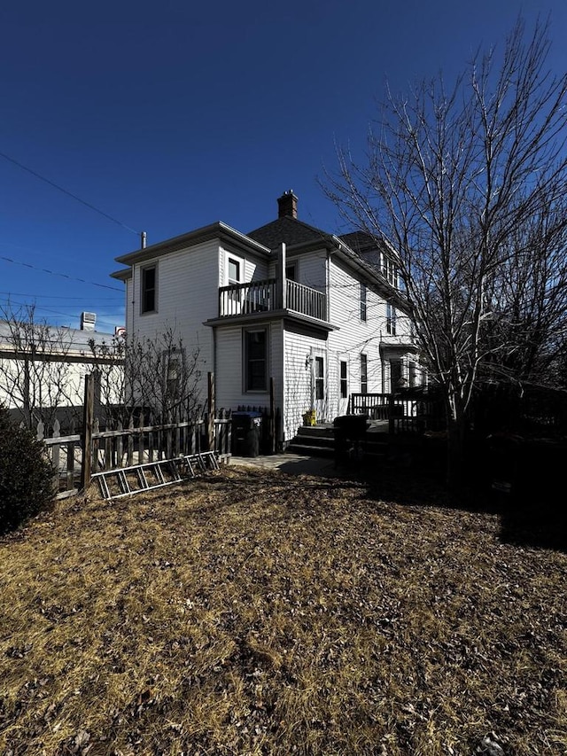 back of property featuring a wooden deck, a balcony, central AC, and a chimney