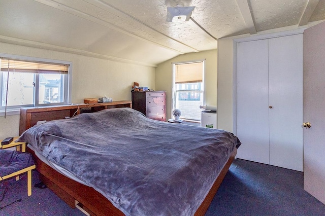 bedroom with a closet, multiple windows, a textured ceiling, and lofted ceiling with beams