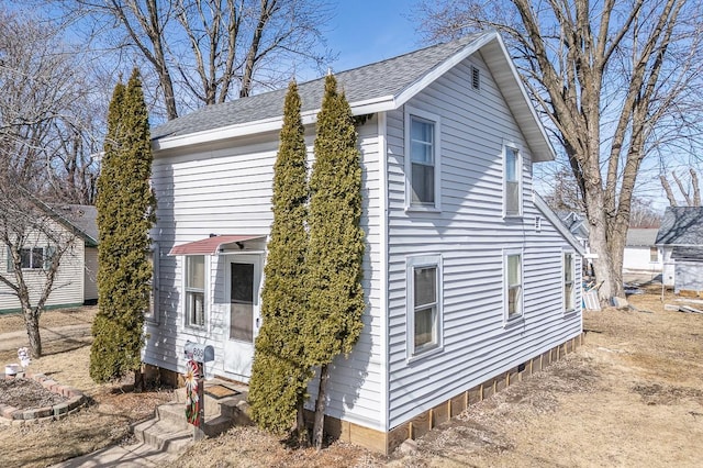 view of property exterior featuring entry steps and roof with shingles