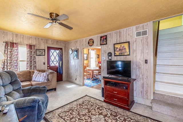 carpeted living room featuring a ceiling fan, visible vents, and a textured ceiling