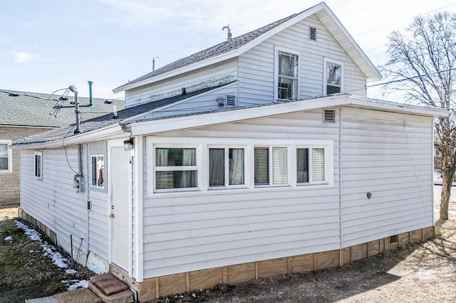 view of home's exterior with a shingled roof and crawl space