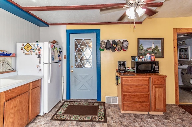 kitchen featuring visible vents, freestanding refrigerator, ceiling fan, black microwave, and brown cabinets