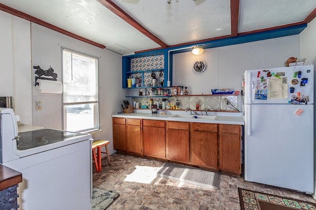 kitchen with beamed ceiling, light countertops, brown cabinetry, white appliances, and a sink