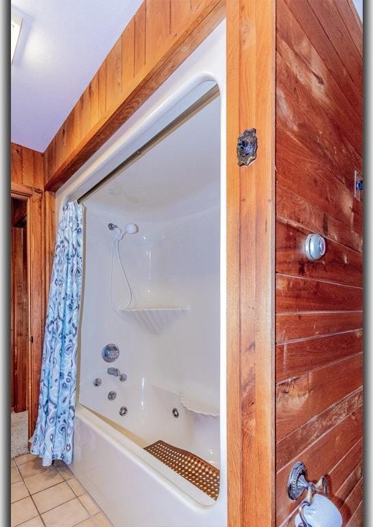 full bathroom with shower / bath combo, wood walls, and tile patterned flooring