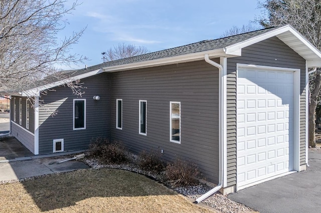 view of property exterior featuring a detached garage and a shingled roof