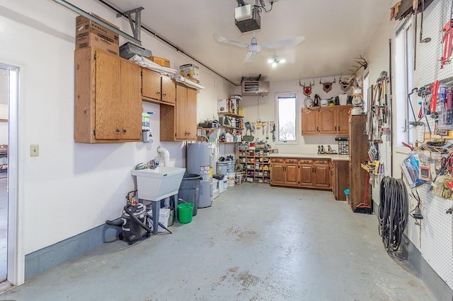 garage with a ceiling fan, a garage door opener, water heater, a workshop area, and baseboards