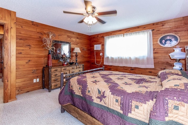 carpeted bedroom with wooden walls, a textured ceiling, an AC wall unit, and ceiling fan