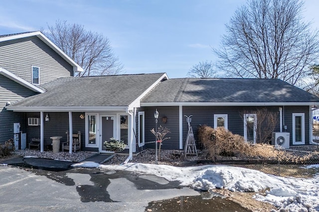 view of front of property featuring a porch, ac unit, and roof with shingles