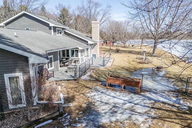 view of snow covered exterior with fence, a chimney, roof with shingles, and a wooden deck