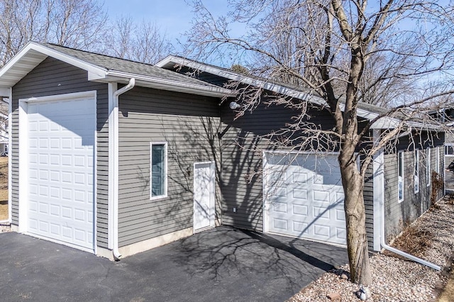 view of property exterior featuring a garage and roof with shingles