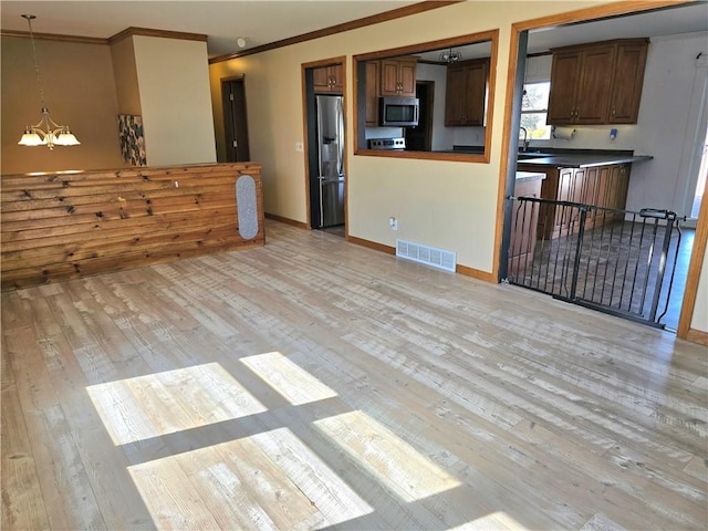 living room with visible vents, light wood finished floors, baseboards, an inviting chandelier, and crown molding