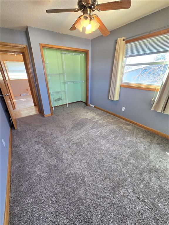 unfurnished bedroom featuring a ceiling fan, carpet, a closet, and baseboards