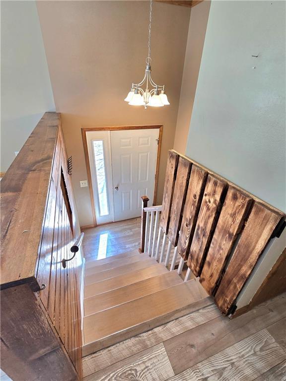 foyer entrance with stairway, an inviting chandelier, and hardwood / wood-style floors