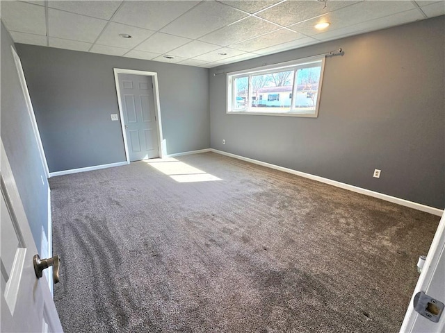 spare room with a drop ceiling, carpet, and baseboards