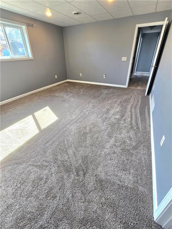 unfurnished room featuring carpet, baseboards, and a drop ceiling