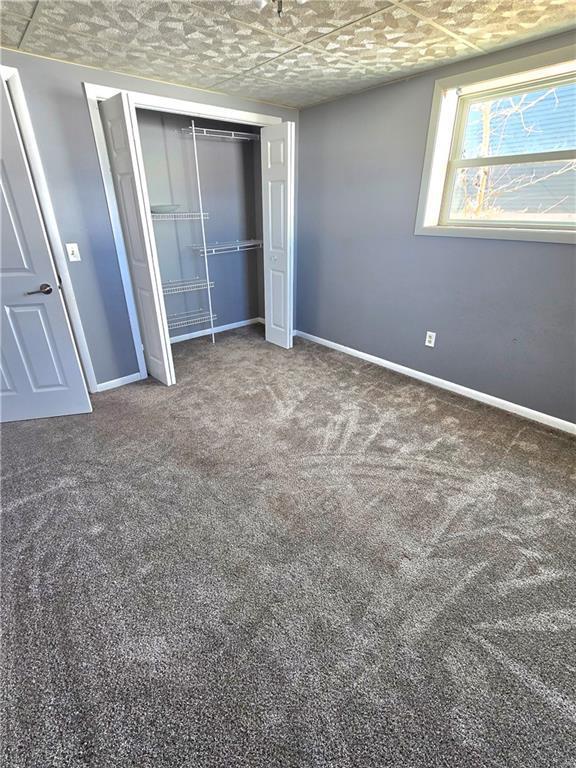 unfurnished bedroom featuring a closet, baseboards, and carpet floors