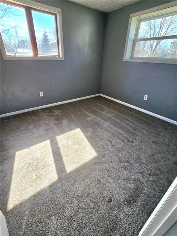 carpeted empty room featuring baseboards