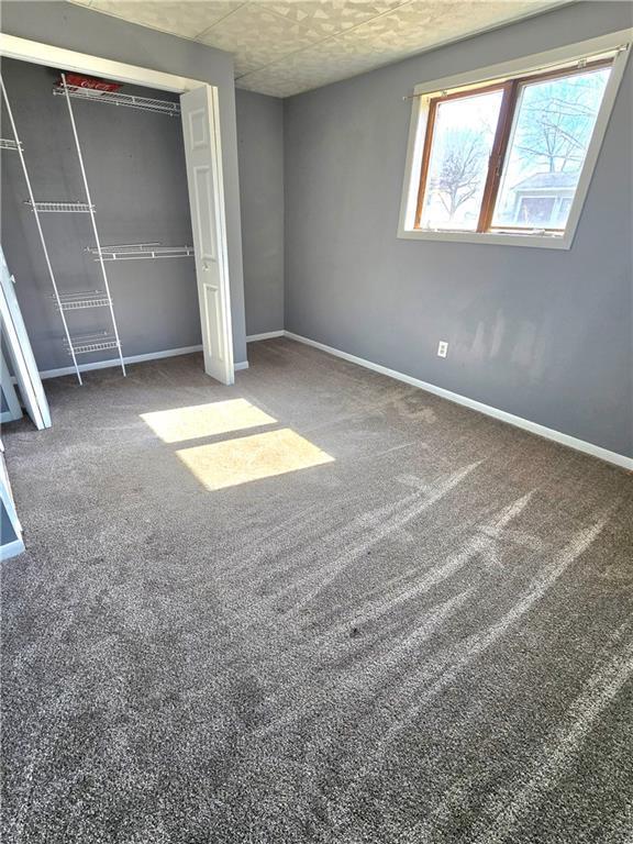 unfurnished bedroom featuring a closet, baseboards, and carpet