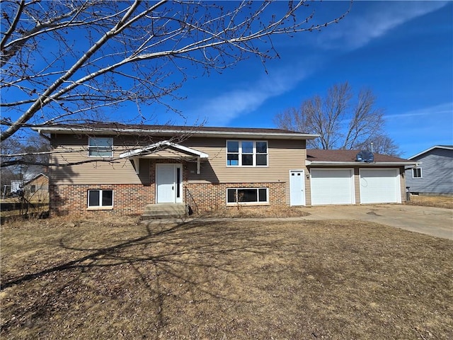 split foyer home with brick siding, an attached garage, and driveway