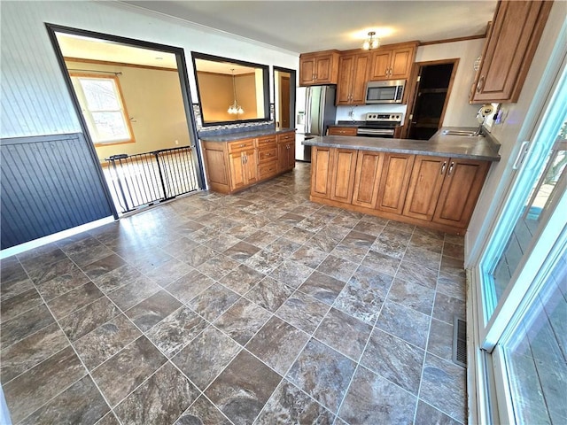 kitchen with visible vents, crown molding, brown cabinets, appliances with stainless steel finishes, and a peninsula