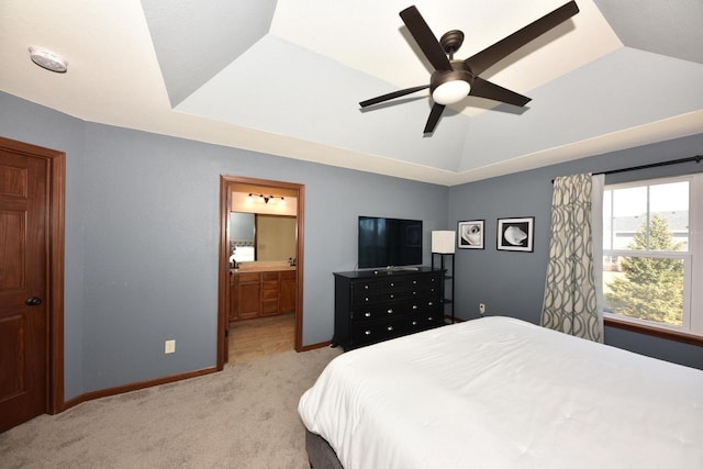 bedroom featuring baseboards, a tray ceiling, vaulted ceiling, light carpet, and ensuite bath