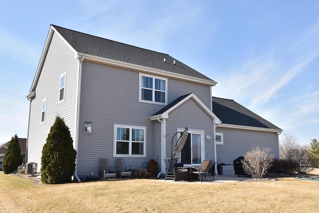 rear view of house with a patio, cooling unit, a lawn, and roof with shingles