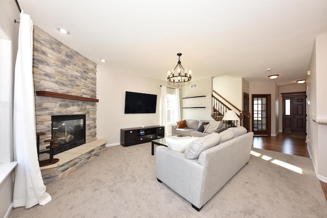 carpeted living room with an inviting chandelier, stairway, a fireplace, and a wealth of natural light